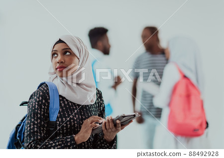 African female student with group of friends in background wearing traditional Islamic hijab clothes. Selectve focus African female student with group of friends in background wearing traditional Islamic hijab clothes. Selectve focus 88492928