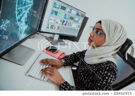 Young Afro-American modern Muslim businesswoman wearing a scarf in a creative bright office workplace with a big screen. 88492955
