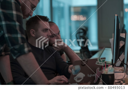 A photo of three men staring intently at a computer while sitting in a modern office. Selective focus A photo of three men staring intently at a computer while sitting in a modern office. Selective focus 88493013