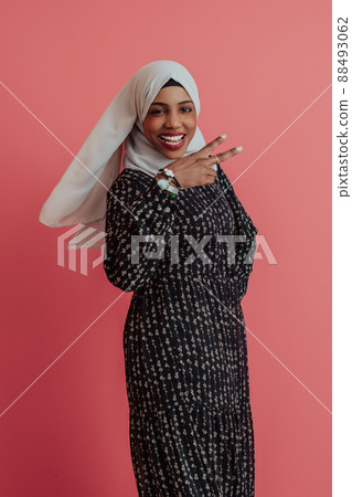 Portrait of young modern muslim afro beauty wearing traditional islamic clothes on plastic pink background. Selective focus  88493062
