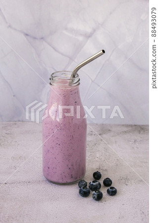 Blueberry smoothie topped with blueberries. A glass of breakfast protein smoothie drink made from pureed raw blueberries, banana, milk, yogurt, and cottage cheese. 88493079