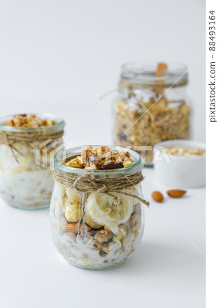 Healthy breakfast. Oatmeal Granola with greek yogurt and nuts banana muesli in jars on light background. Vegan, vegetarian and weight loss diet concept. Detox menu. Healthy breakfast. Oatmeal Granola with greek yogurt and nuts banana muesli in jars on light background. Vegan, vegetarian and weight loss diet concept. Detox menu. 88493164