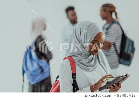 African female student with group of friends in background wearing traditional Islamic hijab clothes. Selectve focus  88493412