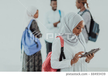 African female student with group of friends in background wearing traditional Islamic hijab clothes. Selectve focus  88493439