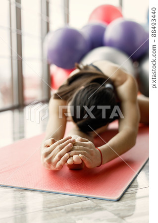 Fitness girl working out at gym with big window. Girl wearing black leggins and sport top. Young woman sitting on a twine. 88493440