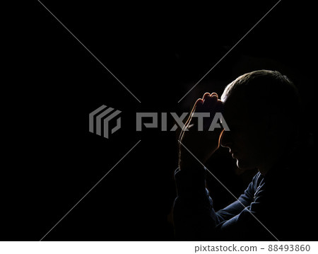 Young man praying on dark background Young man praying on dark background 88493860