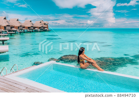 Luxury resort travel vacation destination idyllic overater bungalow villa woman relaxing by infinity pool. Social media influencer traveler luxurious high end lifestyle Luxury resort travel vacation destination idyllic overater bungalow villa woman relaxing by infinity pool. Social media influencer traveler luxurious high end lifestyle 88494710