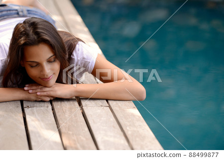 Ah, this is divine.... An attractive young woman lying on her stomach beside the swimming pool. Ah, this is divine.... An attractive young woman lying on her stomach beside the swimming pool. 88499877