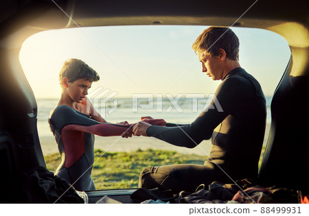 Thats what big brothers are for. Shot of a young surfer helping his little brother put on his wetsuit at the beach. Thats what big brothers are for. Shot of a young surfer helping his little brother put on his wetsuit at the beach. 88499931
