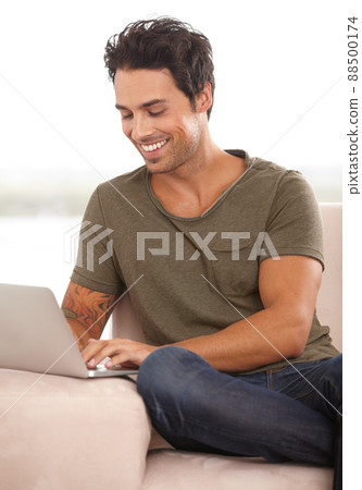 A friendly e-mail. A handsome young man working on his laptop at home. A friendly e-mail. A handsome young man working on his laptop at home. 88500174