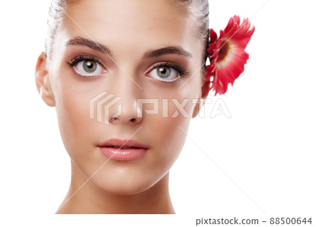Natural beauty. Studio portrait of a beautiful young woman with a flower behind her ear. 88500644