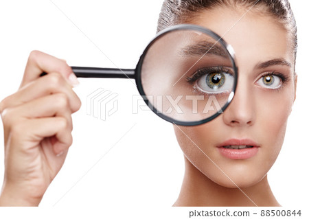Magnifying her best features. Studio shot of a beautiful woman with a magnifying glass in front of her eye. 88500844