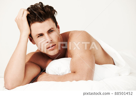 Effortless good looks. A handsome male lying in his bed with no shirt on and looking at the camera. Effortless good looks. A handsome male lying in his bed with no shirt on and looking at the camera. 88501452