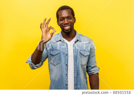 Everything is fine. Portrait of satisfied handsome man in denim shirt with rolled up sleeves smiling and showing approval, ok gesture, agree with suggestion. studio shot isolated on yellow background Everything is fine. Portrait of satisfied handsome man in denim shirt with rolled up sleeves smiling and showing approval, ok gesture, agree with suggestion. studio shot isolated on yellow background 88501558