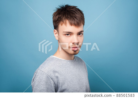 Portrait of concentrated confident brunette man with small beard and mustache in casual sweater looking attentively with intelligent serious expression. indoor studio shot isolated on blue background Portrait of concentrated confident brunette man with small beard and mustache in casual sweater looking attentively with intelligent serious expression. indoor studio shot isolated on blue background 88501583
