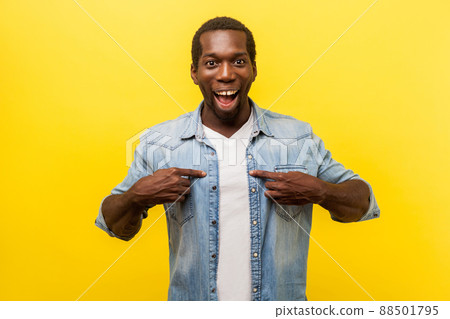 This is me. Portrait of astonished young man in denim casual shirt pointing at himself, looking surprised by victory, rejoicing in achievement. indoor studio shot isolated on yellow background 88501795