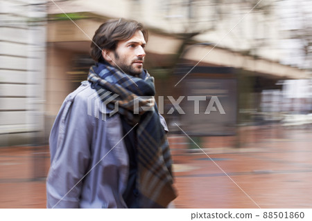City life can be fast-paced. A handsome man walking through an urban area in a hurry. 88501860