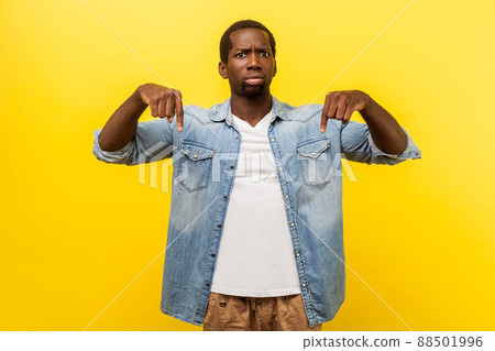 Here and right now. Portrait of bossy man in denim shirt with rolled up sleeves pointing down and giving command to do immediately, control concept. indoor studio shot isolated on yellow background 88501996