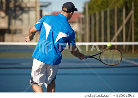 Returning it with force. Rear view of a young man about to hit a tennis ball. Returning it with force. Rear view of a young man about to hit a tennis ball. 88502068