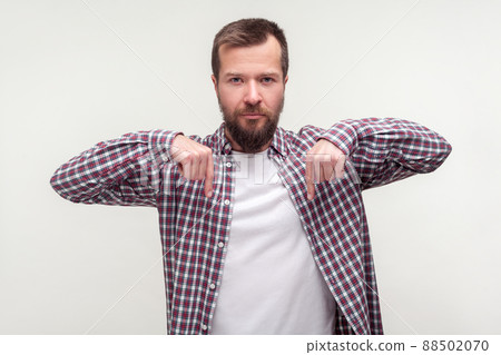 Look down, here and right now. Portrait of bossy strict bearded man in casual plaid shirt pointing fingers down and looking seriously at camera. indoor studio shot isolated on white background Look down, here and right now. Portrait of bossy strict bearded man in casual plaid shirt pointing fingers down and looking seriously at camera. indoor studio shot isolated on white background 88502070