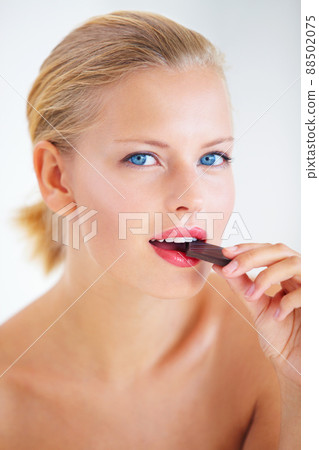Tasting the sweetness. Beautiful young woman enjoying a delicious piece of chocolate. 88502075