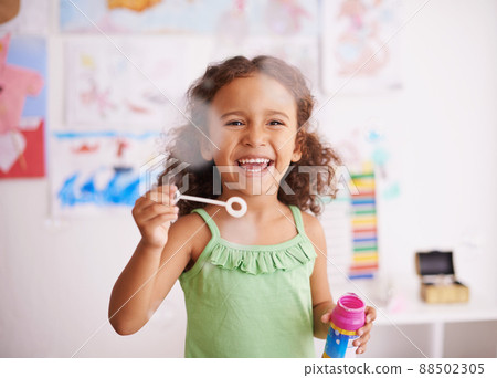Bubbles that pop are funny. Shot of an adorable little girl blowing bubbles in her bedroom. 88502305