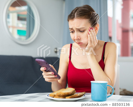 Dissatisfied woman with toothache sitting at dinner table 88503136