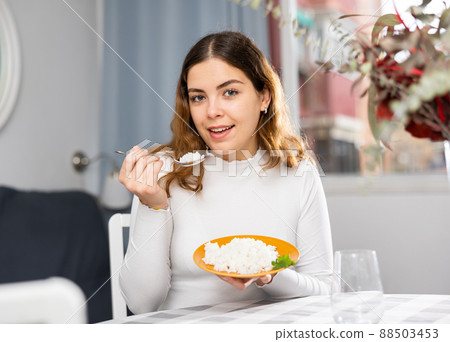 Emotional young woman eating rice at home Emotional young woman eating rice at home 88503453