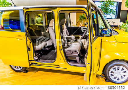 The interior of a yellow high-tall wagon type light car is photographed from the right side. The interior of a yellow high-tall wagon type light car is photographed from the right side. 88504352