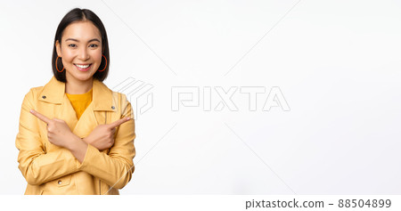 Image of indecisive asian girl, pointing fingers sideways, pointing left and right, choosing variant, deciding, standing over white background Image of indecisive asian girl, pointing fingers sideways, pointing left and right, choosing variant, deciding, standing over white background 88504899