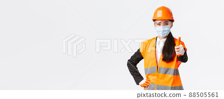 Covid-19 safety protocol at enterpise, construction and preventing virus concept. Confident asian female engineer, architect in face mask and helmet showing thumb-up, guarantee quality of building 88505561