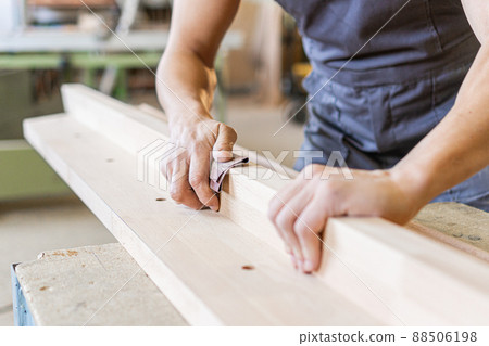 Crop artisan sanding wooden board in workshop 88506198