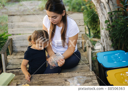 Family sorting garbage at home on backyard. Concept of recycling outdoors. Mom and daughter caring about nature 88506363