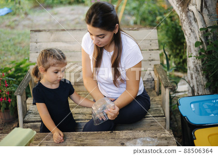 Family sorting garbage at home on backyard. Concept of recycling outdoors. Mom and daughter caring about nature 88506364