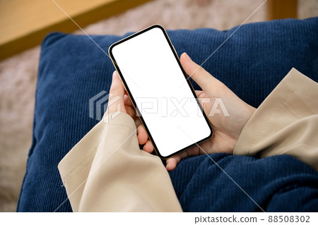 Relaxed woman sitting on a comfy sofa and using smartphone Relaxed woman sitting on a comfy sofa and using smartphone 88508302