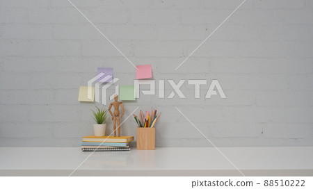 Personal accessories on white table and colorful sticky notes on brick wall background. Copy space for your advertise tex. Personal accessories on white table and colorful sticky notes on brick wall background. Copy space for your advertise tex. 88510222