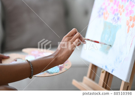 Cropped shot young woman painting picture on canvas with oil paints. 88510398