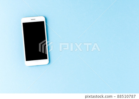 Smart phone with blank screen on blue desktop. Top view Smart phone with blank screen on blue desktop. Top view 88510787
