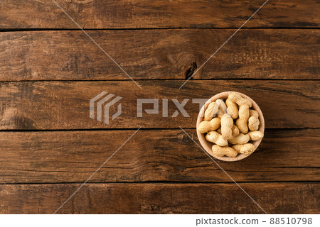 Tasty peanuts in bowl on wooden background with copyspace. Top view 88510798