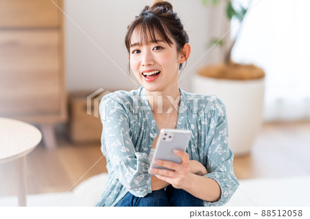 A young woman operating a smartphone 88512058
