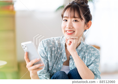 A young woman operating a smartphone 88512060