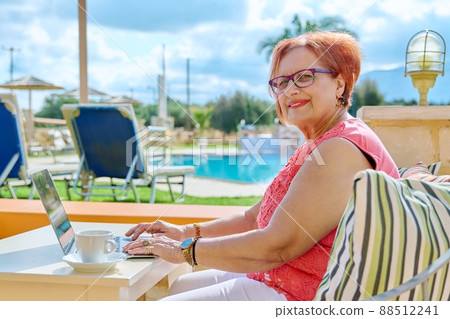 Beautiful elderly pension age woman sitting outdoor with laptop. Beautiful elderly pension age woman sitting outdoor with laptop. 88512241