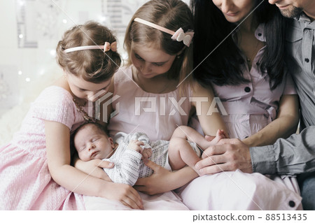 family and a newborn baby in the hands of his older sisters. 88513435