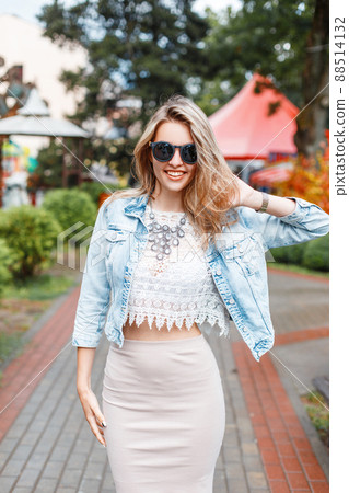 Elegant happy young hipster woman with beautiful smile in stylish clothes in sunglasses on a walk in an amusement park on a summer sunny day. Stylish positive girl on vacation. Great weekend. Elegant happy young hipster woman with beautiful smile in stylish clothes in sunglasses on a walk in an amusement park on a summer sunny day. Stylish positive girl on vacation. Great weekend. 88514132