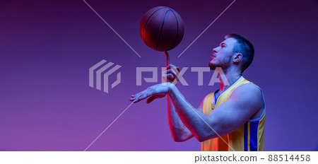Spin. Studio shot of muscled man, basketball player training with ball isolated on purple background in neon light. Goals, sport, motion, activity concepts. 88514458