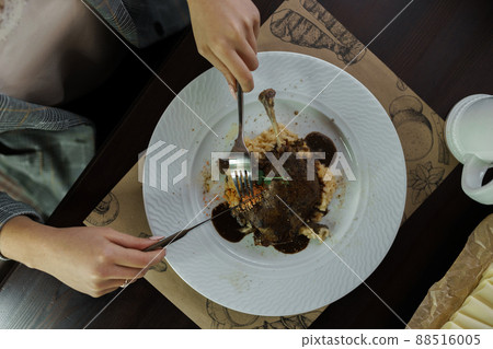 Woman sits at a wooden table in a cafe and eating a grilled duck with porridge in wine sauce. Hot delicious lunch. lifestyle 88516005