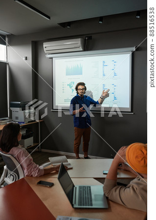 Young mixed race analyst pointing at projection screen while presenting statistics at staff meeting 88516538