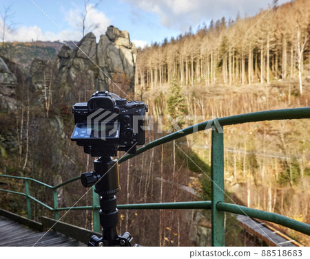 Camera on a tripod films a rock scenery behind a green railing Camera on a tripod films a rock scenery behind a green railing 88518683