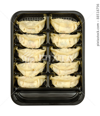 Gyoza, Japanese dumplings, in a black plastic tray. Uncooked, filled dumplings, ready to boil or fry. Filling, wrapped in thin batter. Close-up, from above, isolated on white background, food photo. 88518756