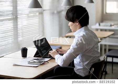 Asian programmer writing code on a laptop 88519102